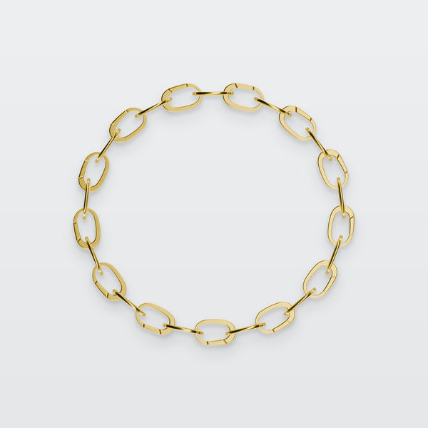 Special Hinged Oval Bracelet in solid gold, photographed flat on a pale grey studio surface
