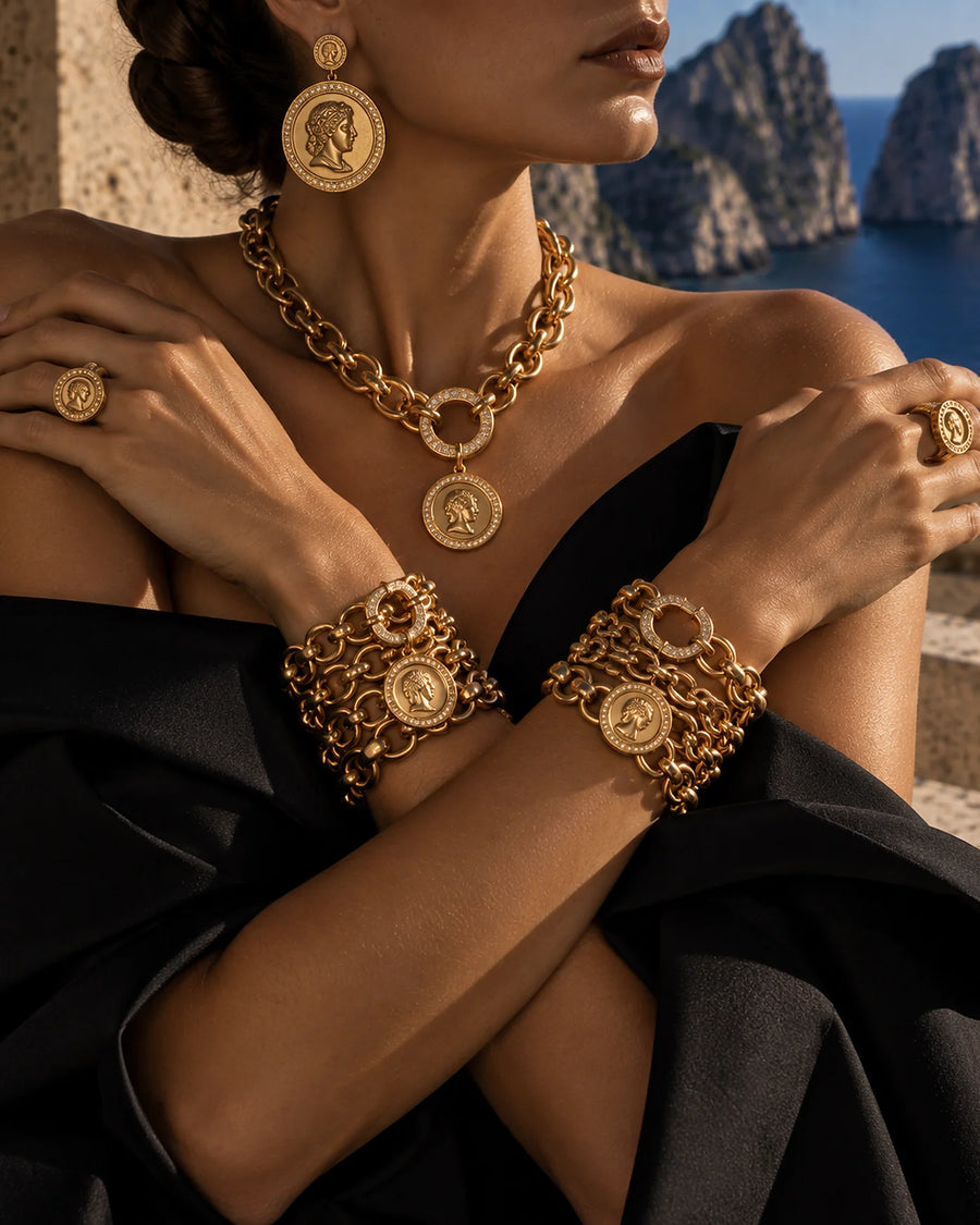 A woman wearing a gold medallion necklace and medallion bracelets on the Greek coast